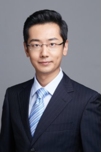 Henan Ma, Originations Risk Manager, in a dark suit, light blue tie, and glasses