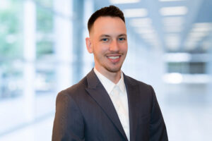 Chase Matheson smiling at the camera in a blue-gray suit jacket and white shirt