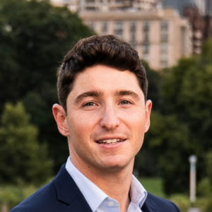 Sam smiling in a suit outside