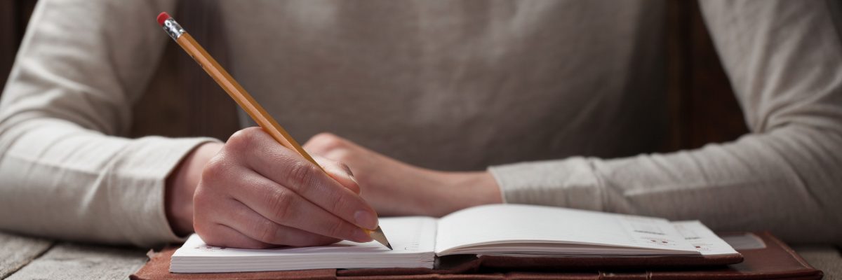 hand writes with a pen in a notebook