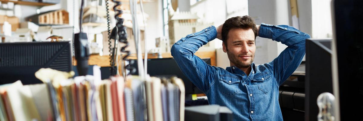 Mid adult businessman sitting relaxed with hands behind head in office